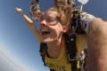 woman doing tandem skydiving attached to instructor